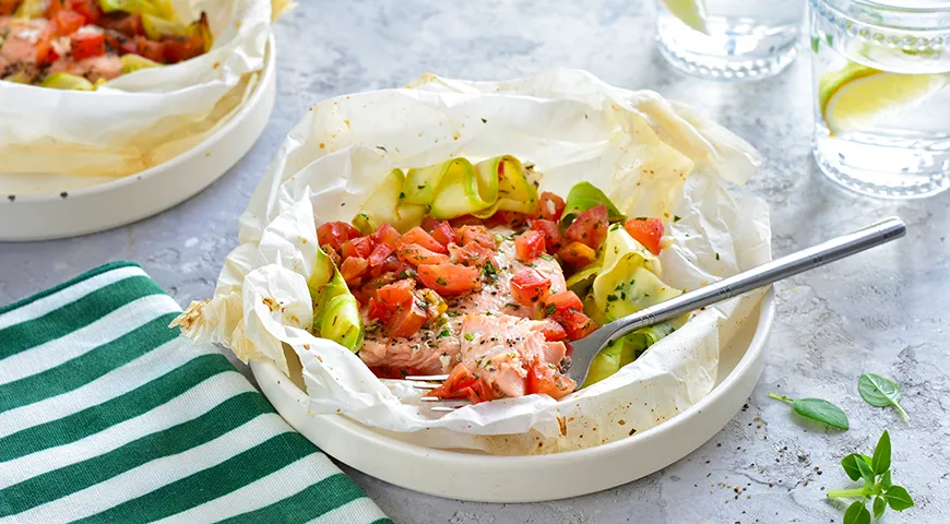 Salmone rosso in pergamena con zucchine, pomodori ed erbe aromatiche